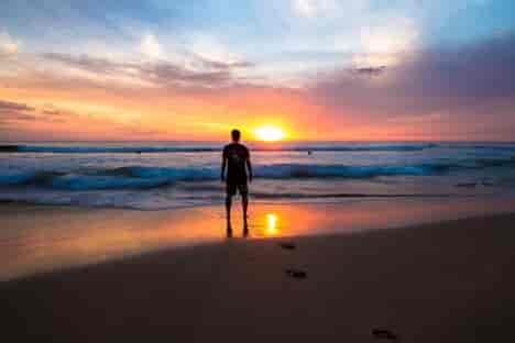man standing on beach with sunset